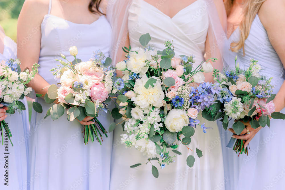 Bride and bridesmaids in lavender dresses in a summertime wedding bouquets with white, pink, and purple flowers and green leaves.