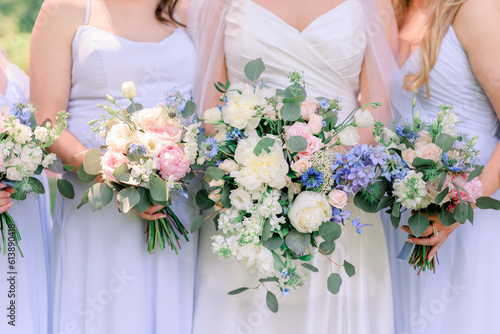 Bride and bridesmaids in lavender dresses in a summertime wedding bouquets with white, pink, and purple flowers and green leaves.