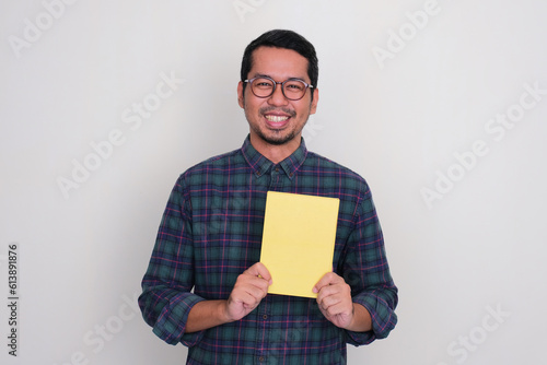 Adult Asian man smiling happy while holding blank achievement certificate photo