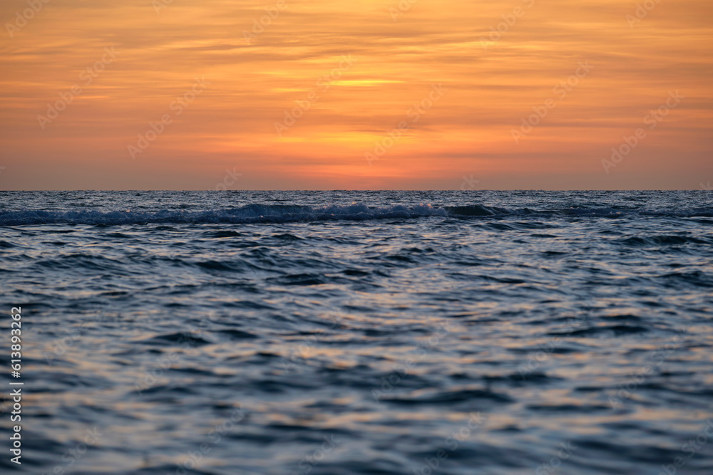 Obraz premium Dramatic red ocean waves at sunset with soft evening sea dark water