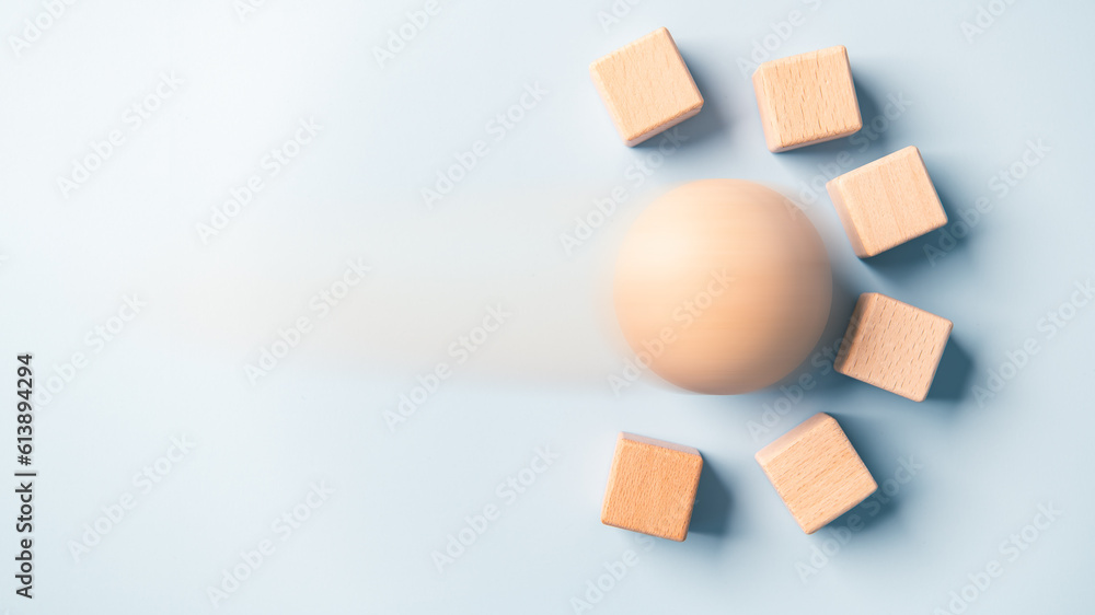 Motion blur of rolling sphere ball crashing blank wooden cube wall blocks high speed blue background. Breakthrough business obstacles disruptive concept. Object creative physics. Kinetic energy theme. Motion blur of rolling sphere ball crashing blank wooden cube wall blocks high speed blue background. Breakthrough business obstacles disruptive concept. Object creative physics. Kinetic energy theme.
