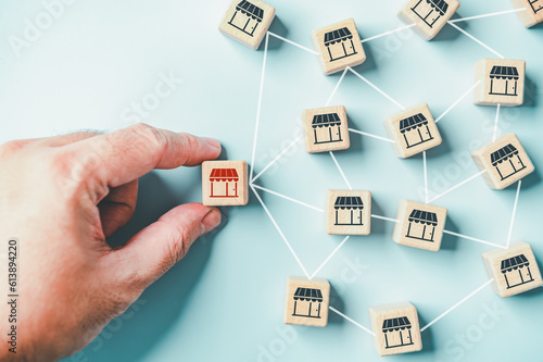 Distribution franchise branch store. Hand placing red franchising shop cube wooden toy block business partner alliance network icon symbol. Market growth expansion financial loan marketing. Copy space photo