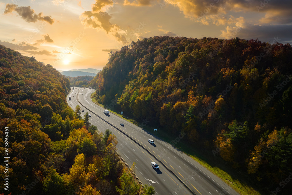 I-40 freeway road leading to Asheville in North Carolina thru Appalachian mountains with yellow fall forest and fast moving trucks and cars. Concept of high speed interstate transportation