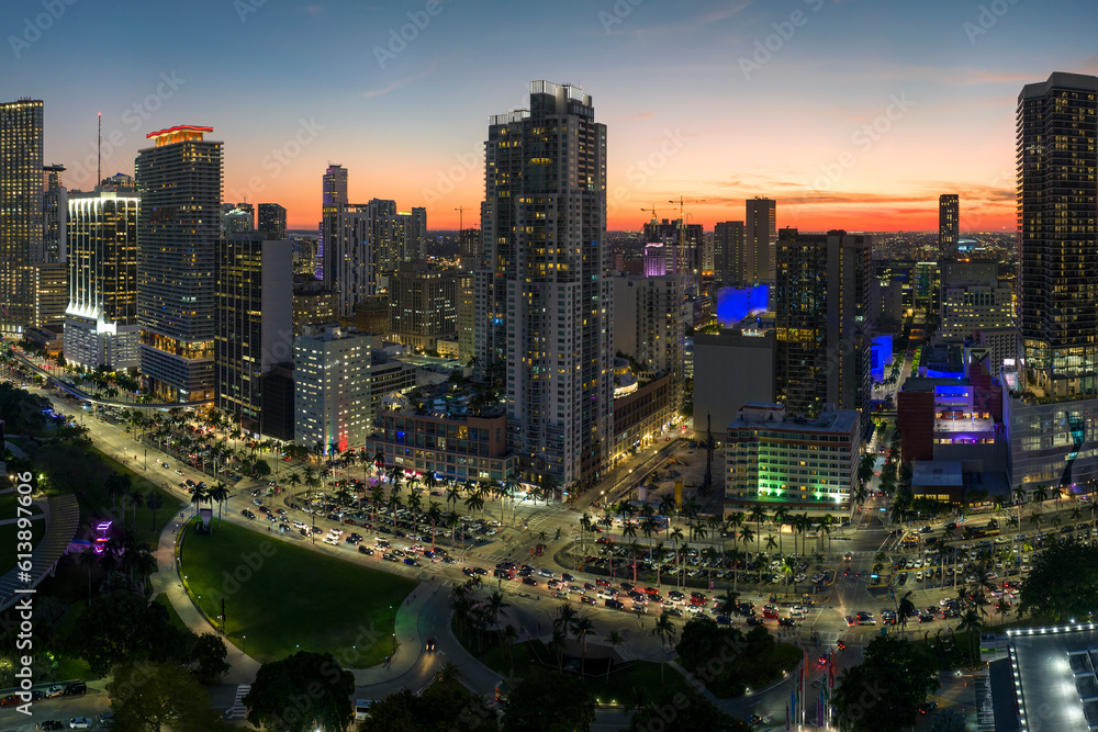 Fototapeta premium View from above of brightly illuminated skyscraper buildings and street traffic in downtown district of Miami Brickell in Florida, USA at night. American megapolis with business financial district