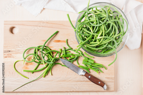 Green garlic scapes on a cutting board. photo