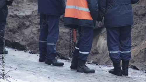 People workers stand at the edge of the pit where work is being done to replace the pipeline. Industry photo