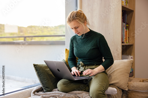 Women's remote work wellness. Work-life balance for women. A woman using laptop in the coziest place. photo