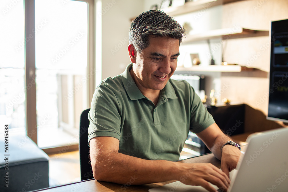 Middle aged man working on his laptop and going over his bills at home