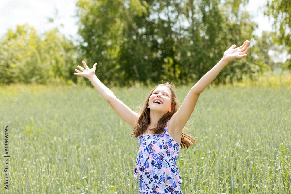 Happy teenage girl laughing happily, closing her eyes, raising her hands up, in a summer park Happy teenage girl laughing happily, closing her eyes, raising her hands up, in a summer park