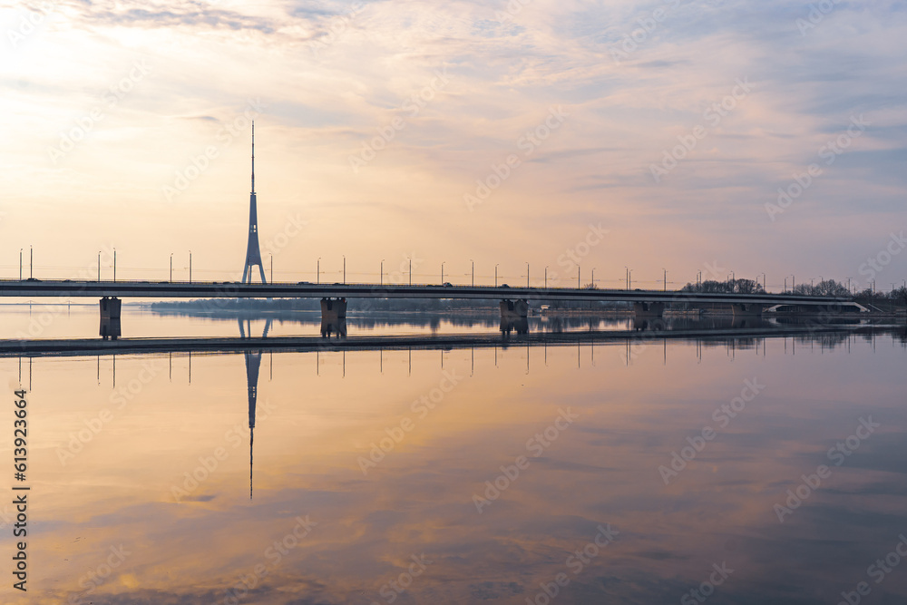sunrise in river Daugava, Riga, reflection of a TV tower and bridge