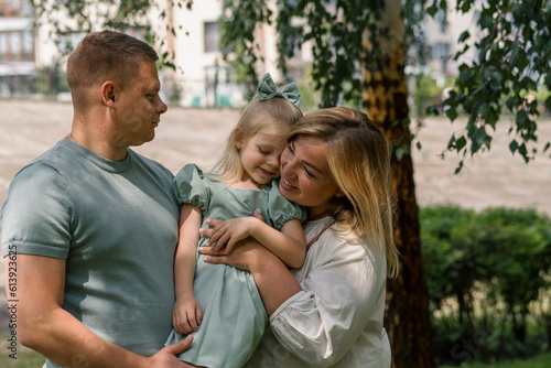 Portrait of a smiling young family mom dad and little daughter family on a walk in the park happy childhood © Guys Who Shoot