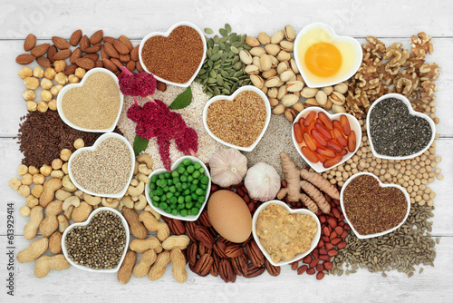 Health food for a healthy heart high in lipids containing essential fatty acids unsaturated good fats for low cholesterol levels with nuts, dairy, grain, seeds, vegetables and vitamin e capsules.
