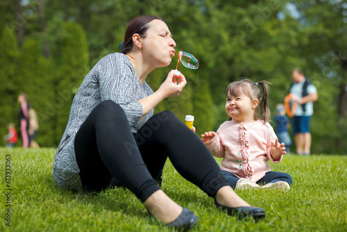 Mom together with her little girl blowing soap bubbles in the park