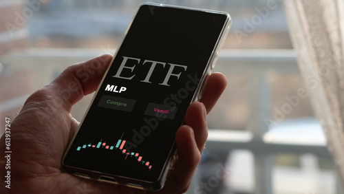 Fototapeta Naklejka Na Ścianę i Meble -  An investor analyzing an etf fund on a phone. Italian text: MLP, buy, sell.