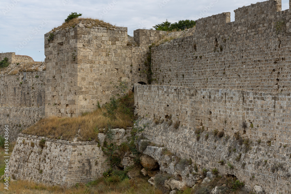 Empty street in old town in Rhodes, Greece surrounded by fortification stone walls