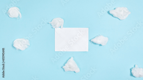 White paper closed envelope flies through white clouds on a blue background. Concept of delivering mail, letters and messages.
