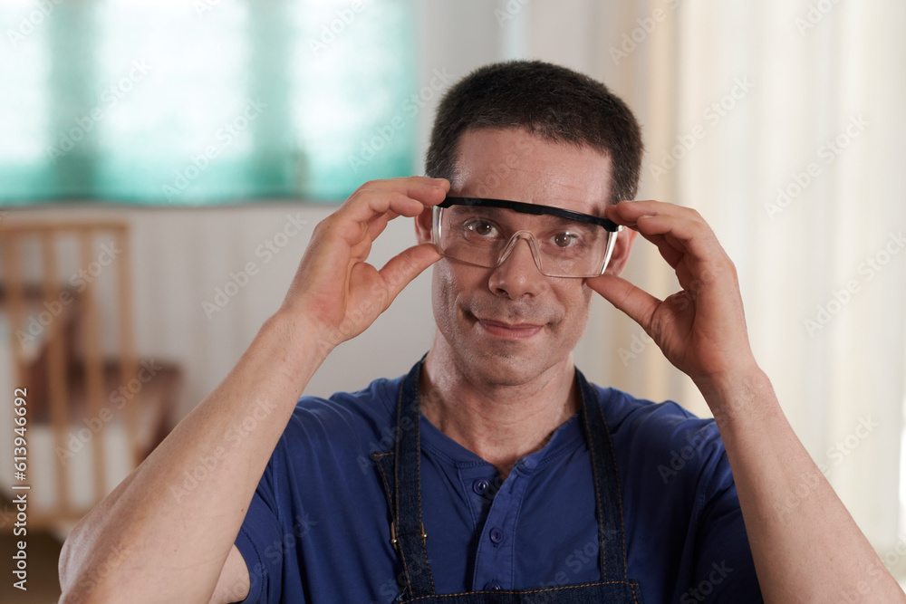 Portrait of young worker looking at camera while wearing protective glasses to work Portrait of young worker looking at camera while wearing protective glasses to work