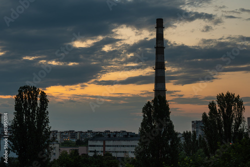 Large brick industrial chimney against the background of beautiful sky and sunset