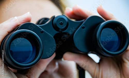A woman peers through binoculars at the horizon of Lake Superior