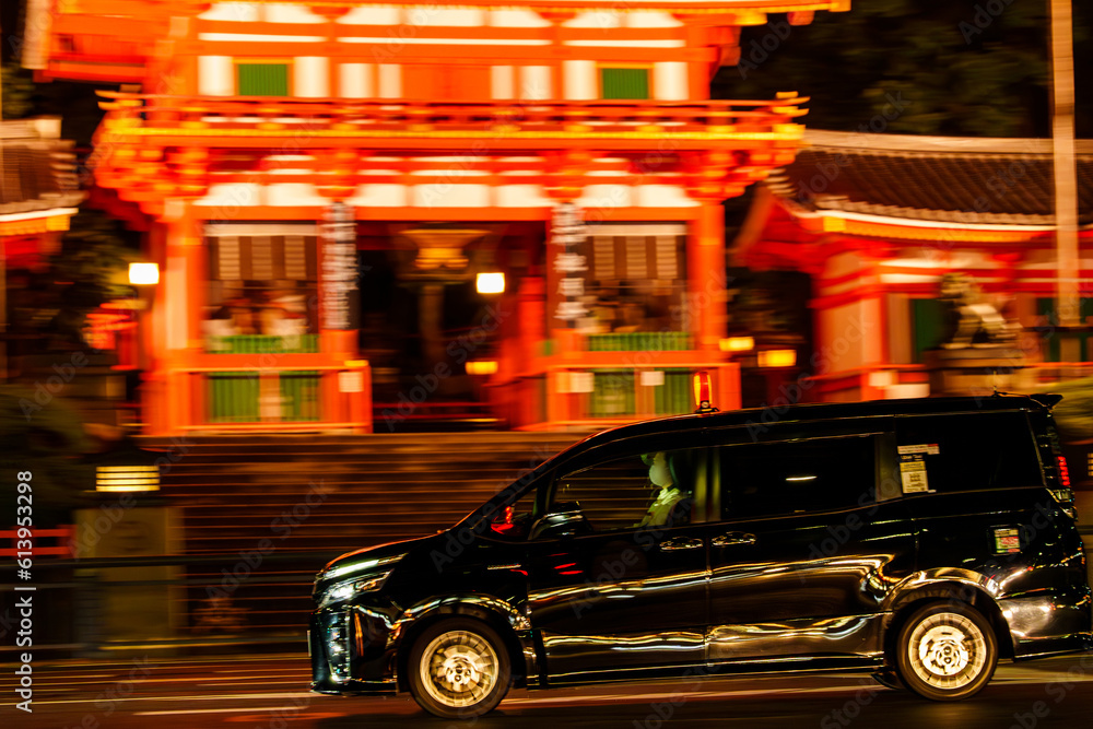 京都の夜の街を走る黒塗りのタクシー