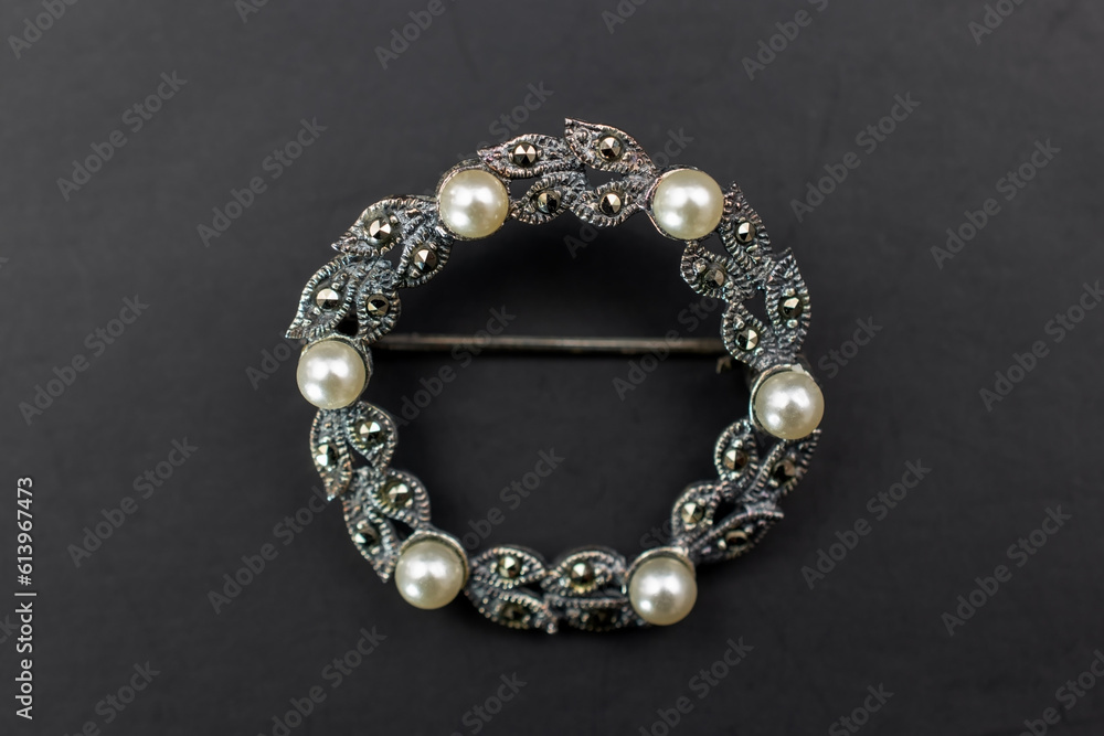 Obraz premium Vintage silver brooch on black background, old accent retro jewelry for women, promotional photo for an online jewellery store