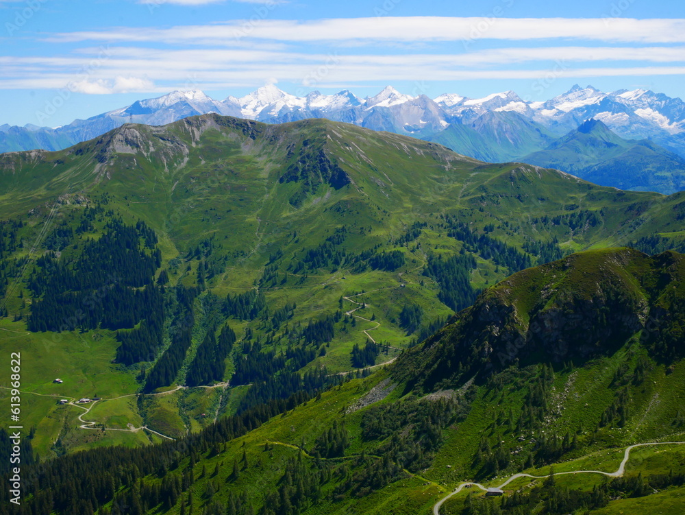 View on mountains near Saalbach Hinterglemm ski resort on a summer day,green meadows,mountains, blue sky, clouds, Hohen Tauern mountains with glaciers in background.  Alps, Austria.  .
