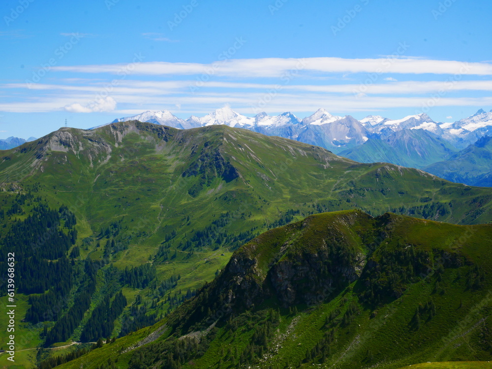 Obraz premium View on mountains near Saalbach Hinterglemm ski resort on a summer day,green meadows,mountains, blue sky, clouds, Hohen Tauern mountains with glaciers in background. Alps, Austria. .