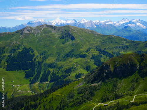 View on mountains near Saalbach Hinterglemm ski resort on a summer day,green meadows,mountains, blue sky, clouds, Hohen Tauern mountains with glaciers in background. Alps, Austria. .