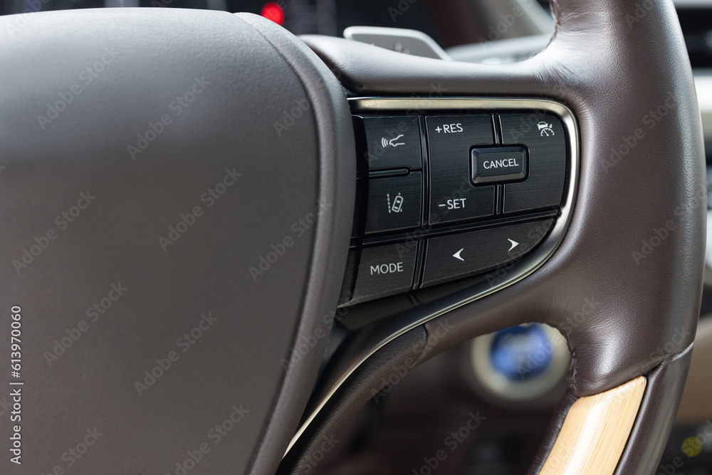 Cruise control, speed limit and volume buttons on modern car steering wheel, interior details. Hybrid car with adaptive cruise control radar. Buttons on the steering wheel