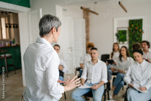 coach training speak explain question to group of employees at seminar