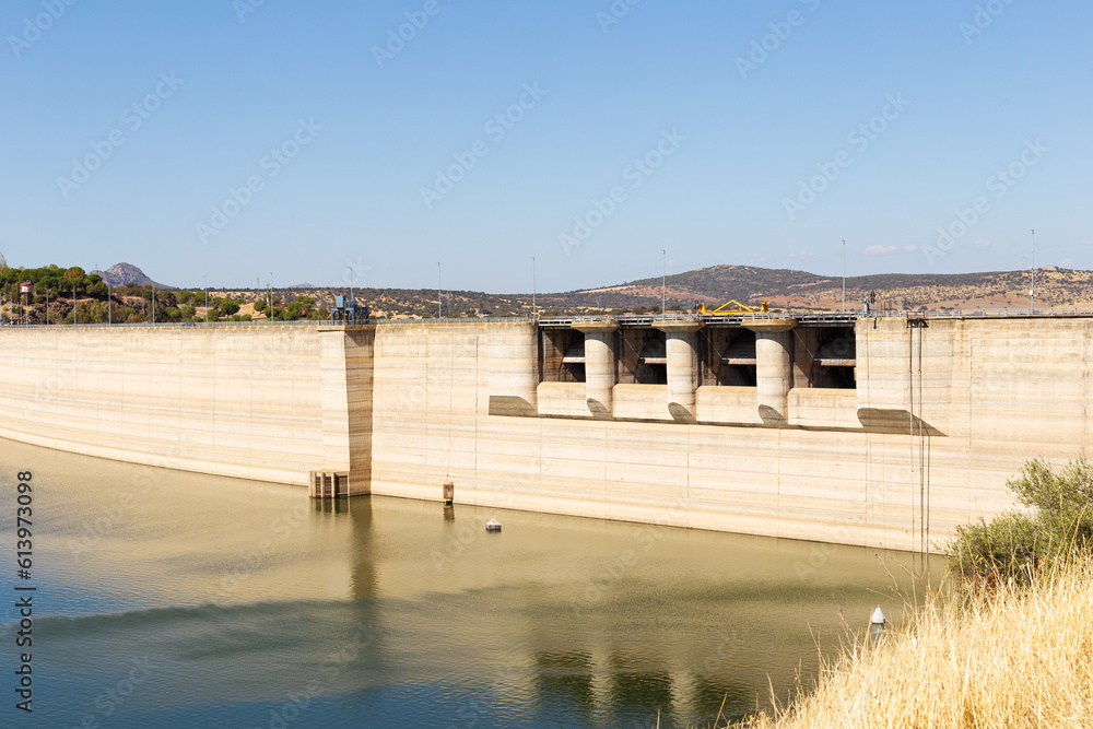 Close-up of swamp dam in area where it contains water. Hydroelectric power station. Water level is high. Blue sky. Extremadura, Spain.