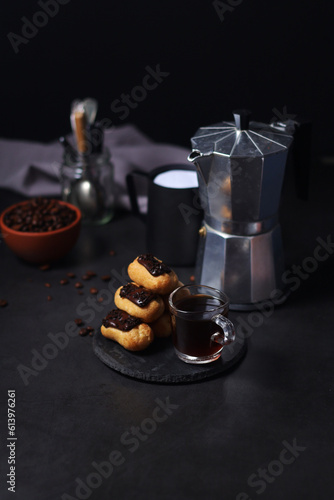 Chocolate eclairs with a cup of coffee and a coffee pot