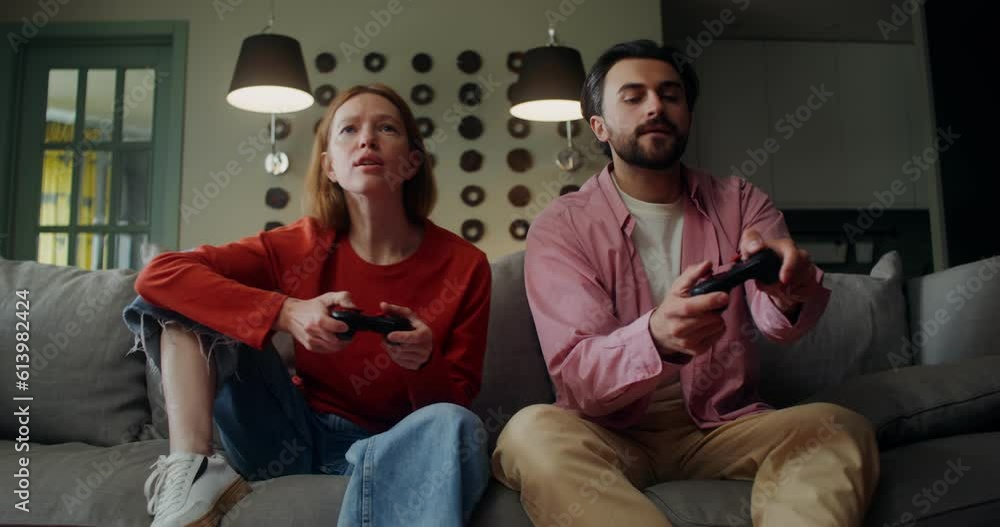 A man and a woman play video games with a joystick while sitting on the couch with a concentrated look, and then the woman wins A man and a woman play video games with a joystick while sitting on the couch with a concentrated look, and then the woman wins
