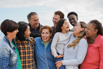 Crowd of multi generational people hugging each other outdoor - Multiracial friends having fun together