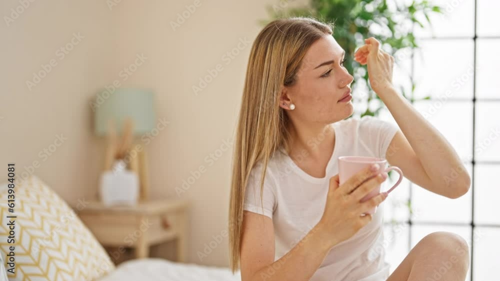 Young blonde woman drinking cup of coffee sitting on bed at bedroom Young blonde woman drinking cup of coffee sitting on bed at bedroom