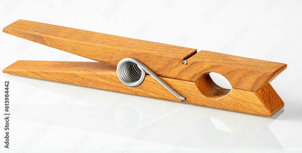 Large wooden clothespin in a bright color with a reflection in a white mirror background Large wooden clothespin in a bright color with a reflection in a white mirror background