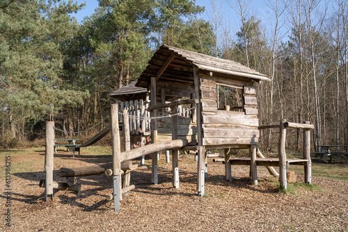 Wooden playground for children with play house, climbing frame and a slide in the park