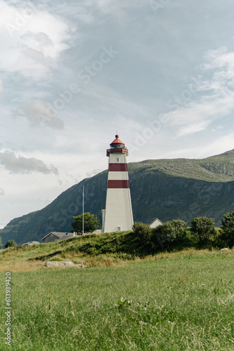 A small lighthouse on the island with mountain in the background and cloudy sky
