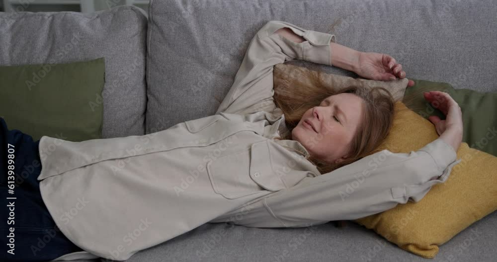 Exhausted mature woman relaxing, lying on a sofa at home. Exhausted mature woman relaxing, lying on a sofa at home.