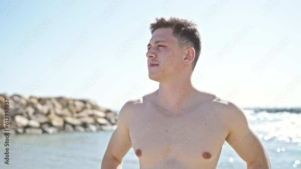 Young hispanic man tourist standing with relaxed expression combing hair with hands at seaside Young hispanic man tourist standing with relaxed expression combing hair with hands at seaside