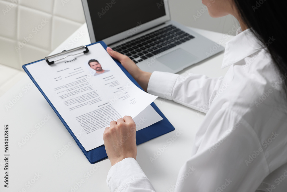 Human resources manager reading applicant's resume at white table, closeup Human resources manager reading applicant's resume at white table, closeup