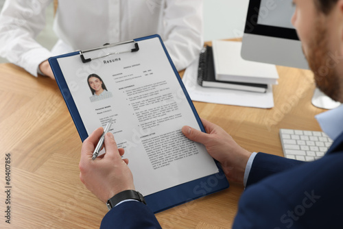 Human resources manager reading applicant's resume in office, closeup