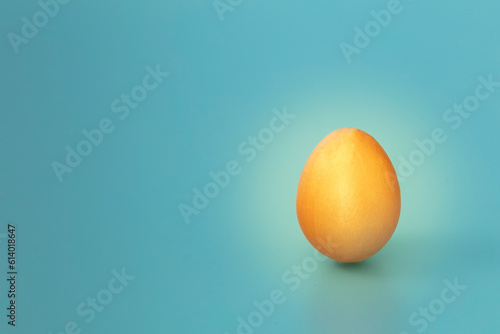 Golden egg isolate on blue background. Copy space. Horizontal.