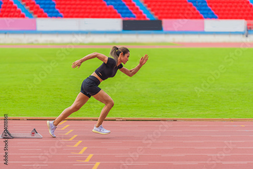 Asian female athlete accelerates during her speed running practice on the stadium track, embodying determination