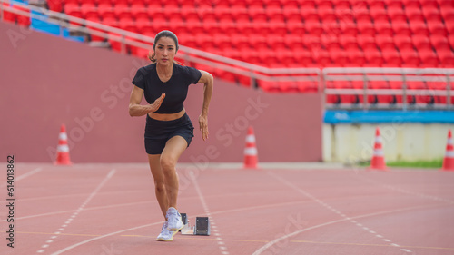 Asian female athlete accelerates during her speed running practice on the stadium track, embodying determination