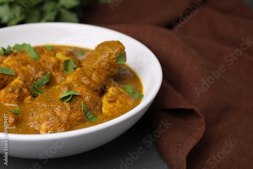Delicious chicken with curry sauce on grey wooden table, closeup. Space for text