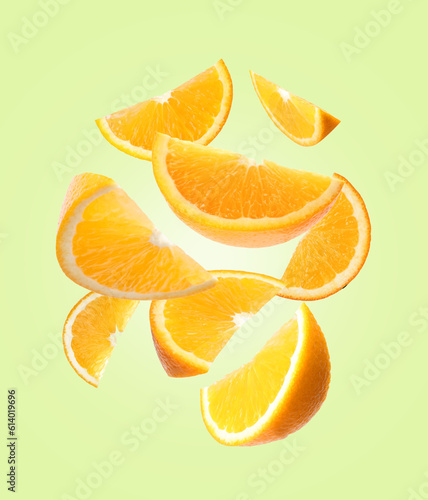Juicy orange slices flying on pale green background