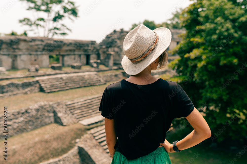 Hiker wonam with a hat looking at ancient Mayan ruins