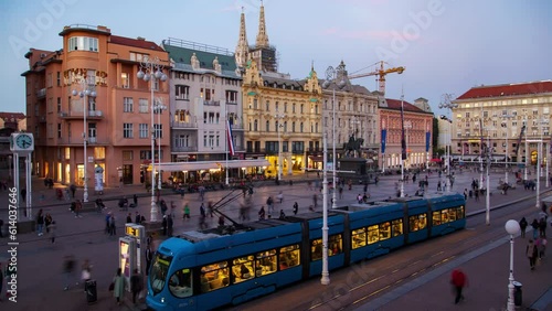In this timelapse, the bustling Ban Jelacic Square in Zagreb, Croatia comes to life with fast-paced trams, people, and clouds during a captivating autumn sunset.