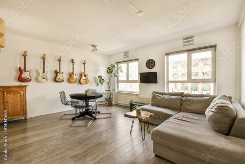 Fototapeta a living room with guitars hanging on the wall and an office chair in the fore -